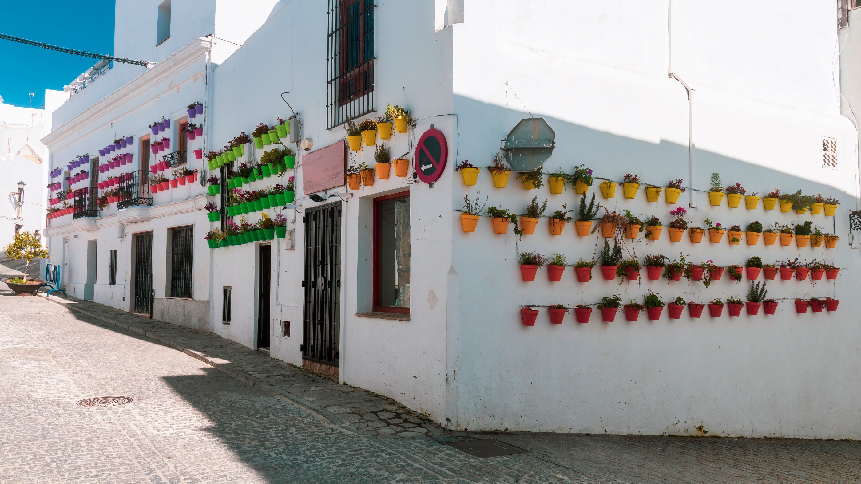 Kullerstensgata med färgglada krukor på fasaderna i Vejer de la Frontera